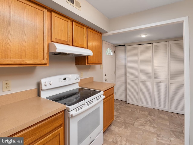 kitchen featuring visible vents, light countertops, under cabinet range hood, and electric range