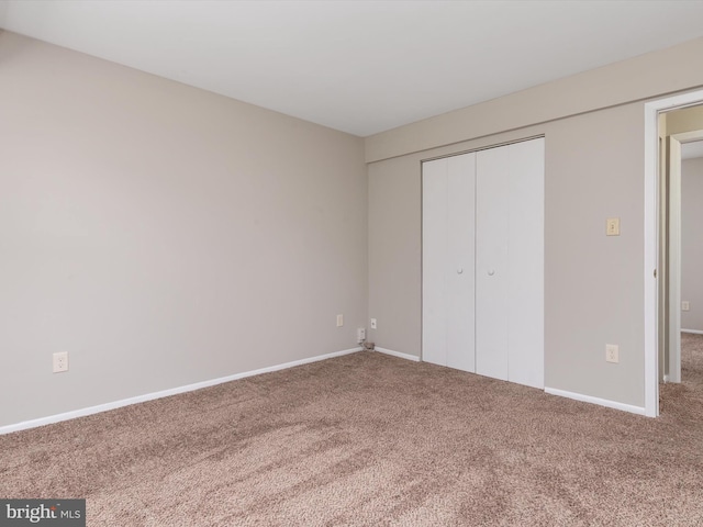 unfurnished bedroom with baseboards, carpet floors, and a closet