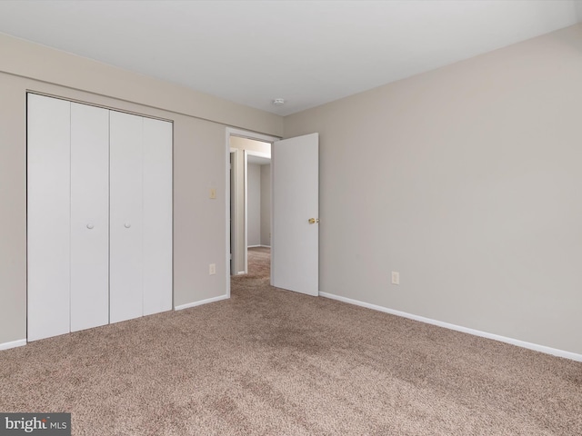 unfurnished bedroom featuring baseboards, carpet flooring, and a closet