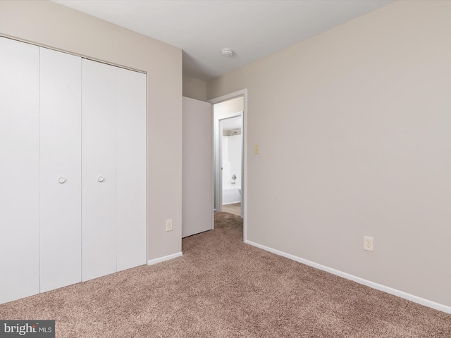 unfurnished bedroom with carpet floors, a closet, and baseboards