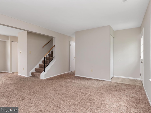unfurnished living room with baseboards, carpet flooring, and stairs