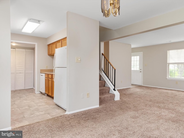 kitchen featuring light colored carpet, baseboards, a notable chandelier, and white appliances