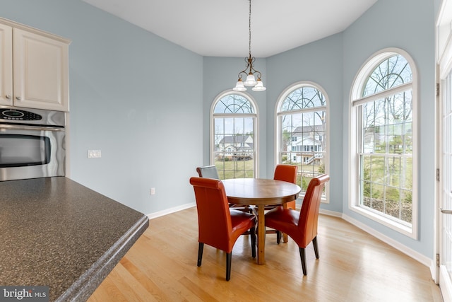 dining area featuring baseboards, a chandelier, and light wood finished floors