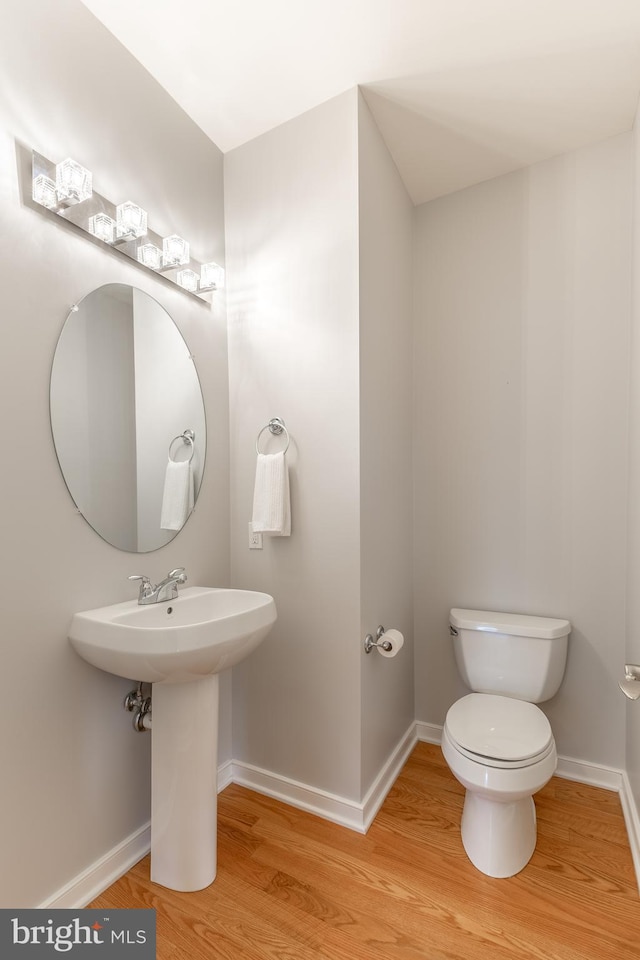 bathroom with toilet, baseboards, and wood finished floors