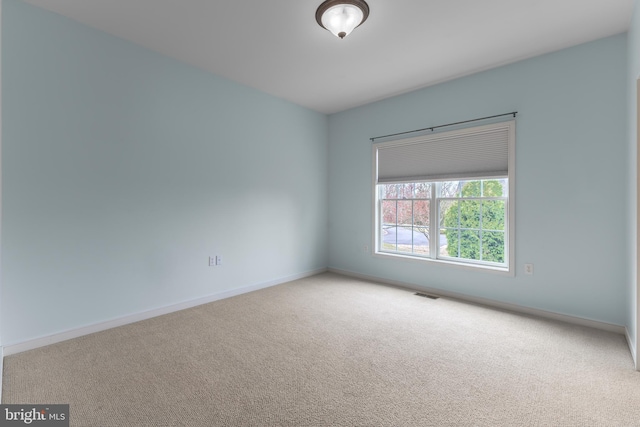 carpeted spare room featuring baseboards and visible vents