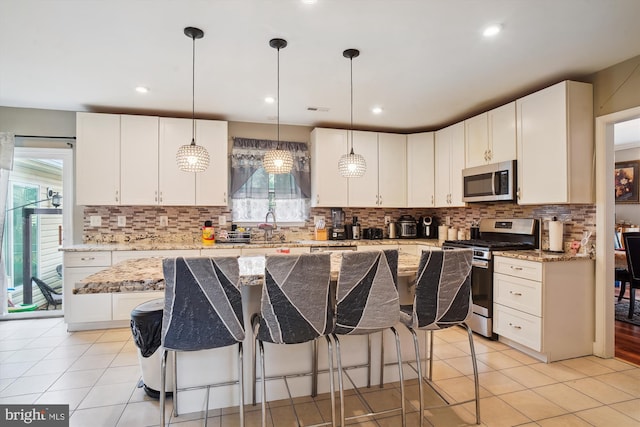 6301 Bradford Ct, Frederick, MD 21701 - kitchen featuring light tile patterned floors, white cabinetry, a kitchen bar, stainless steel appliances, and a sink
