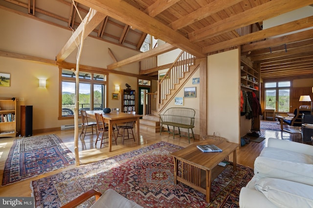 living room with a baseboard radiator, lofted ceiling with beams, stairs, and wood finished floors