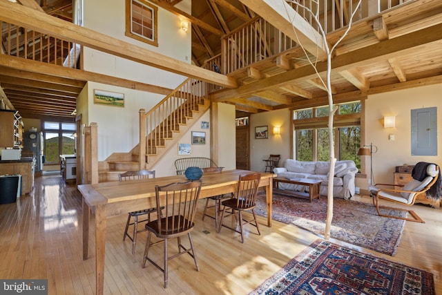 dining space with wood-type flooring, beam ceiling, stairway, and electric panel