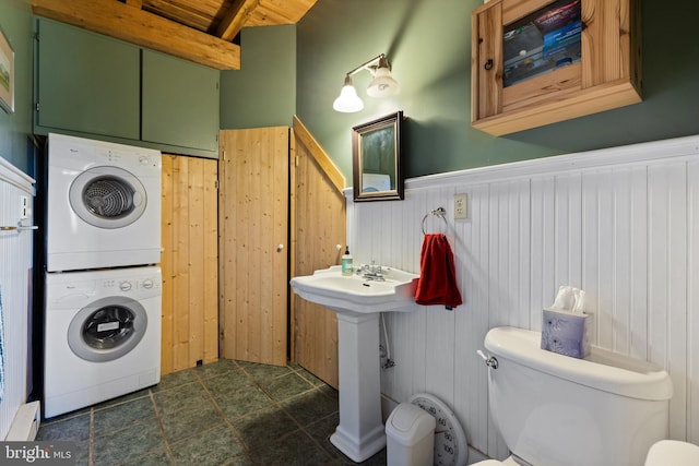 half bathroom with wainscoting, toilet, beamed ceiling, wooden ceiling, and stacked washer / drying machine