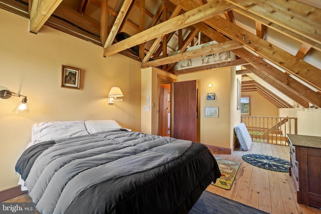 bedroom featuring lofted ceiling with beams and hardwood / wood-style flooring
