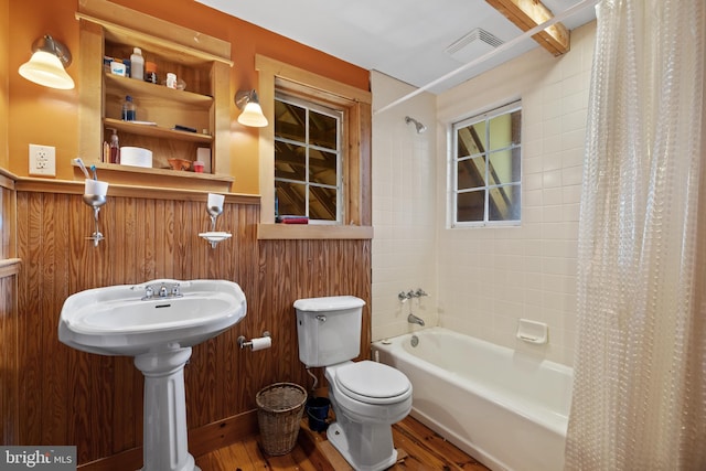 full bath featuring visible vents, shower / bath combo with shower curtain, wood finished floors, toilet, and a sink
