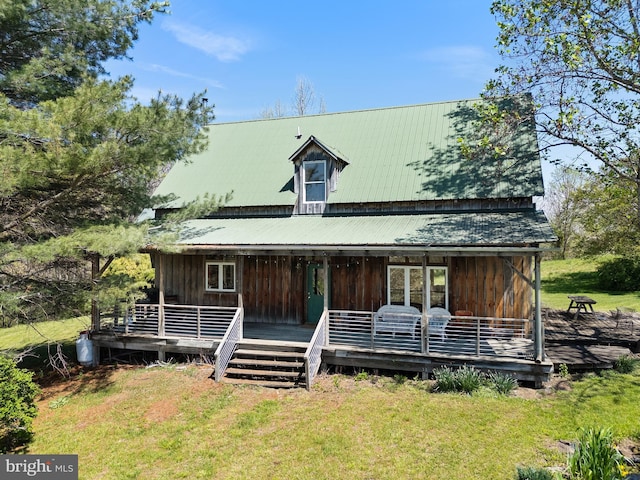 view of front of property with board and batten siding, metal roof, and a front yard