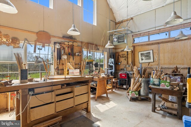 interior space featuring plenty of natural light, concrete floors, a high ceiling, and a workshop area