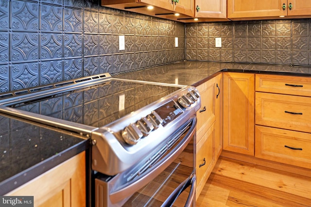 kitchen featuring stainless steel range with electric stovetop, wood finished floors, dark countertops, and backsplash