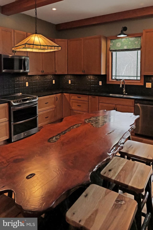 kitchen featuring a sink, dark countertops, tasteful backsplash, and appliances with stainless steel finishes