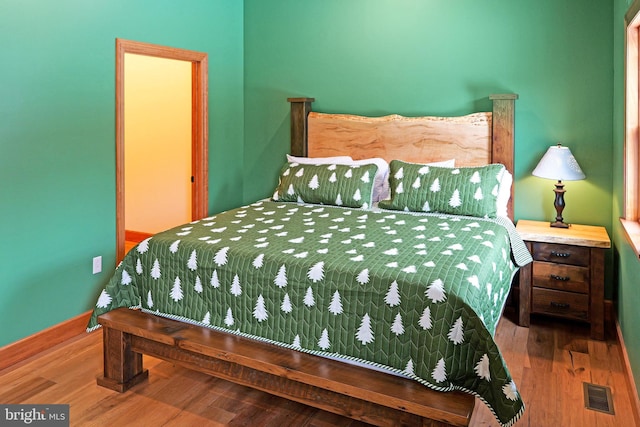 bedroom featuring wood finished floors, baseboards, and visible vents