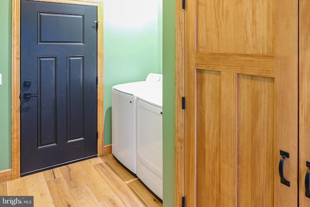 clothes washing area with independent washer and dryer, light wood-style floors, and laundry area