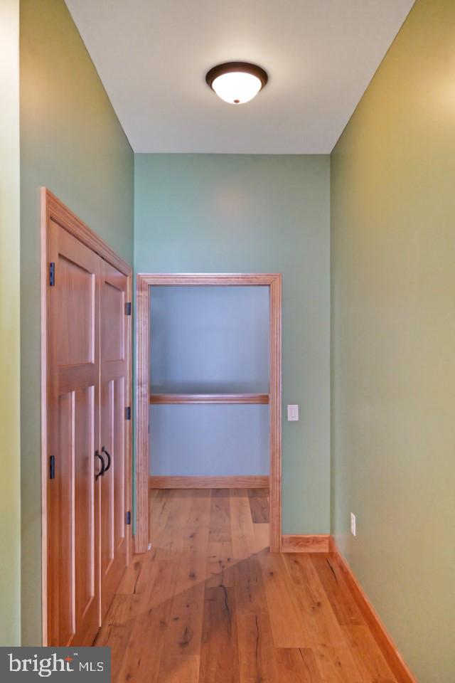 corridor with wood-type flooring and baseboards