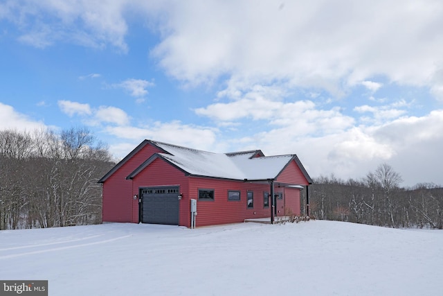 snow covered structure featuring a garage