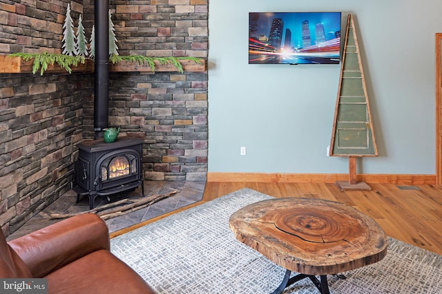 interior space with wood finished floors, baseboards, and a wood stove