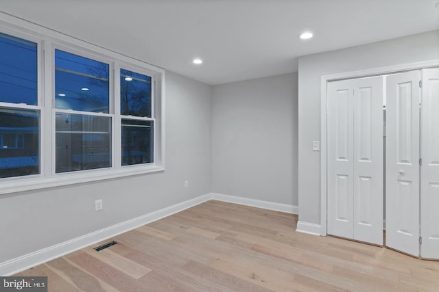 unfurnished bedroom with a closet, baseboards, light wood-style floors, and recessed lighting