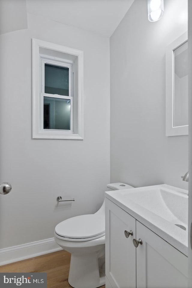 bathroom with toilet, vanity, baseboards, and wood finished floors
