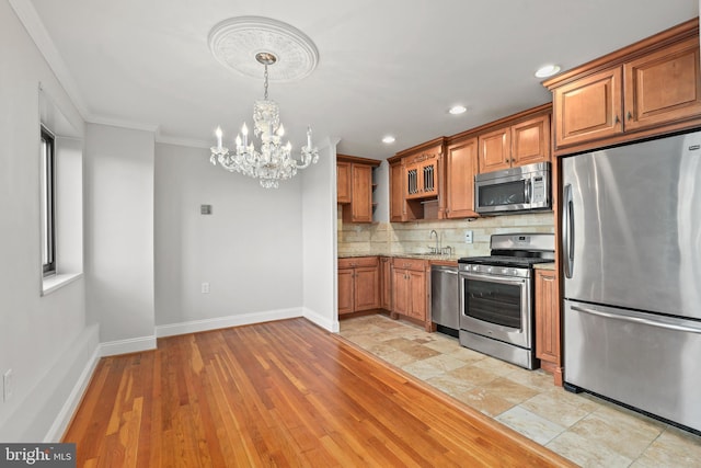 kitchen featuring backsplash, a sink, brown cabinets, stainless steel appliances, and an inviting chandelier