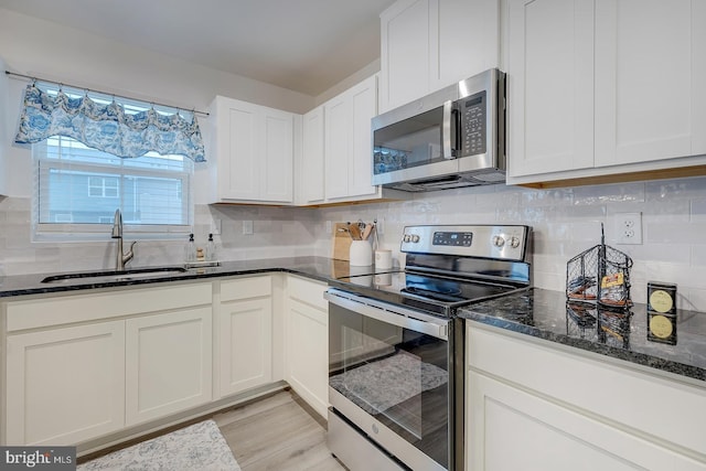 12086 Geyer Ave, Milford, DE 19963 - kitchen featuring dark stone countertops, decorative backsplash, a sink, white cabinets, and appliances with stainless steel finishes