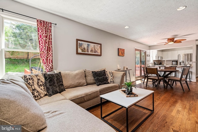living room with a wealth of natural light, a textured ceiling, a ceiling fan, and wood finished floors