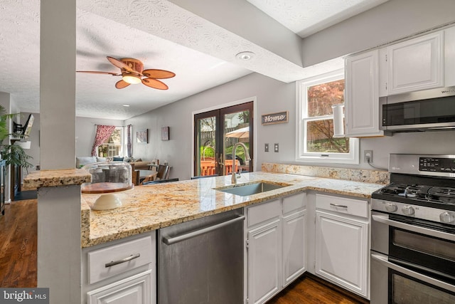 kitchen featuring a sink, light stone countertops, a peninsula, and stainless steel appliances