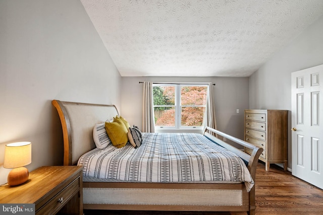 bedroom featuring a textured ceiling, vaulted ceiling, and wood finished floors