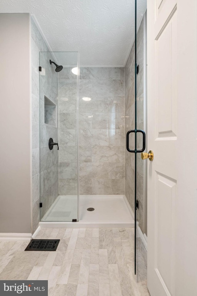 bathroom featuring visible vents, a shower stall, and a textured ceiling