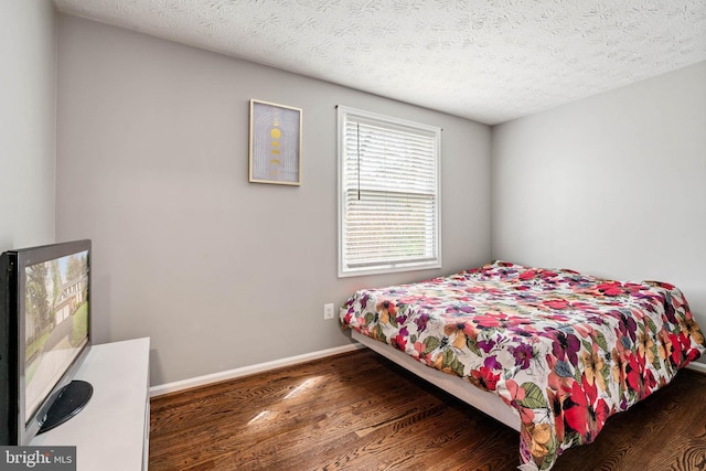 bedroom featuring a textured ceiling, wood finished floors, and baseboards