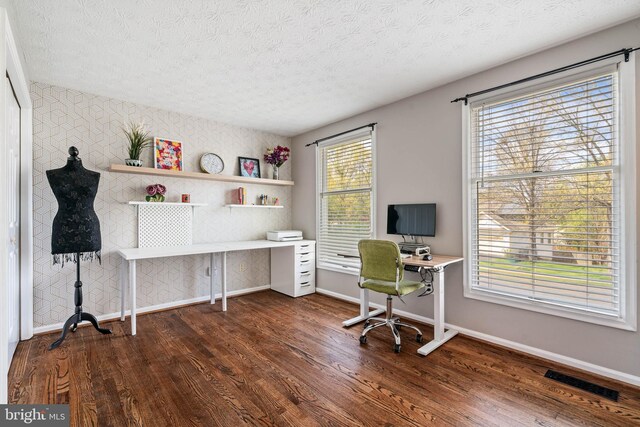 office area featuring baseboards, built in desk, a textured ceiling, dark wood-type flooring, and visible vents