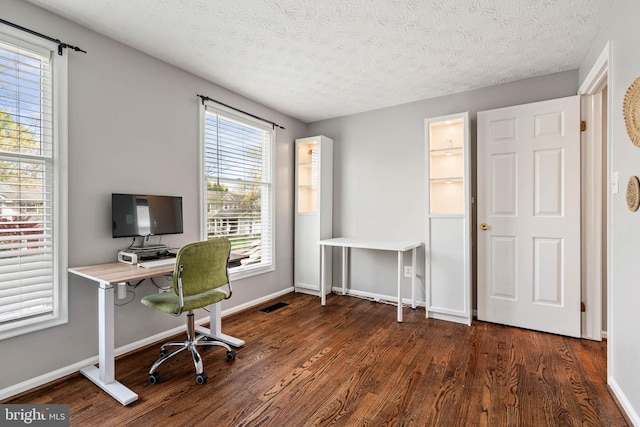 home office with dark wood-type flooring, a textured ceiling, and baseboards