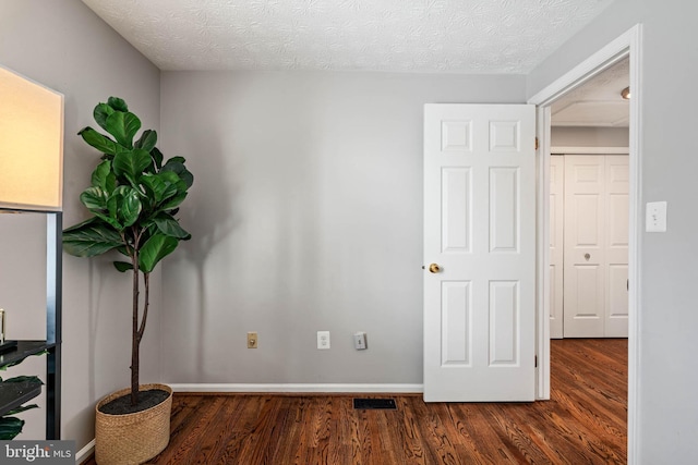 unfurnished bedroom with visible vents, baseboards, wood finished floors, and a textured ceiling