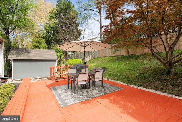 view of patio / terrace with outdoor dining area, a deck, a fenced backyard, and an outbuilding
