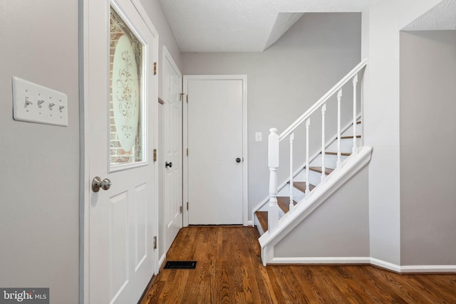 foyer entrance with baseboards, wood finished floors, and stairs