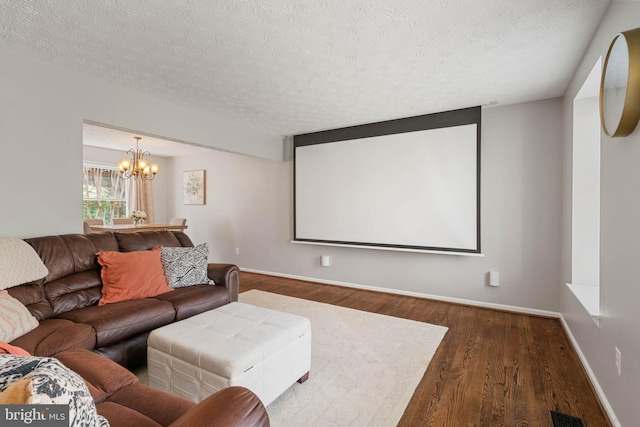 cinema room featuring visible vents, baseboards, a chandelier, a textured ceiling, and wood finished floors