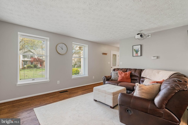 living room with visible vents, baseboards, wood finished floors, and a textured ceiling
