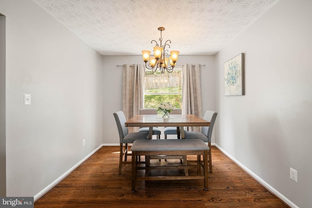 dining space with baseboards, a notable chandelier, wood finished floors, and a textured ceiling