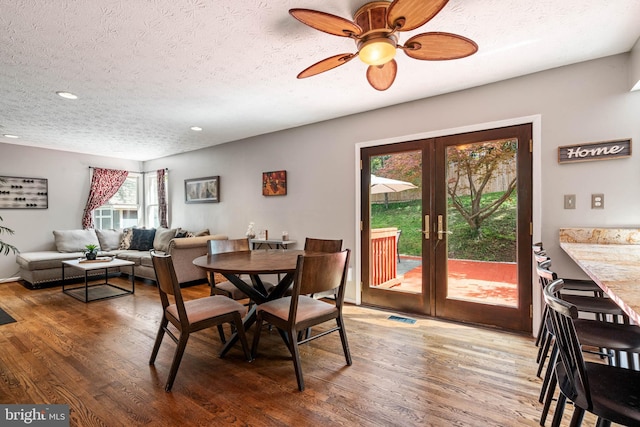dining area with a textured ceiling, french doors, and wood finished floors