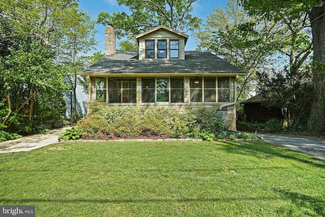 view of front of house with a chimney, a sunroom, and a front yard