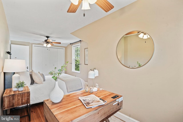 bedroom with wood-type flooring, ceiling fan, baseboards, and a closet