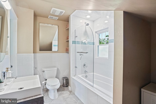 full bathroom with vanity, toilet, tile walls, tiled shower / bath combo, and visible vents