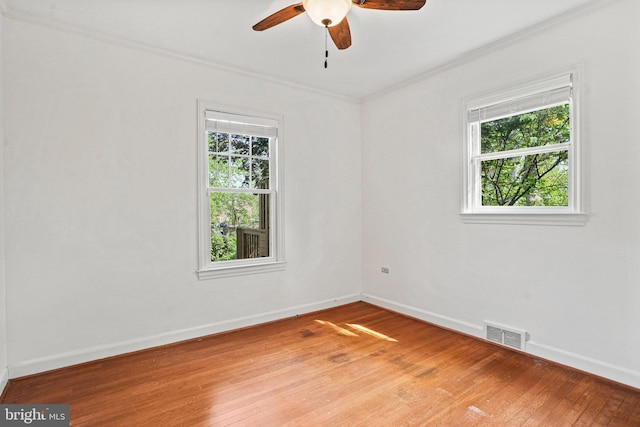empty room featuring crown molding, ceiling fan, light wood-style floors, baseboards, and visible vents
