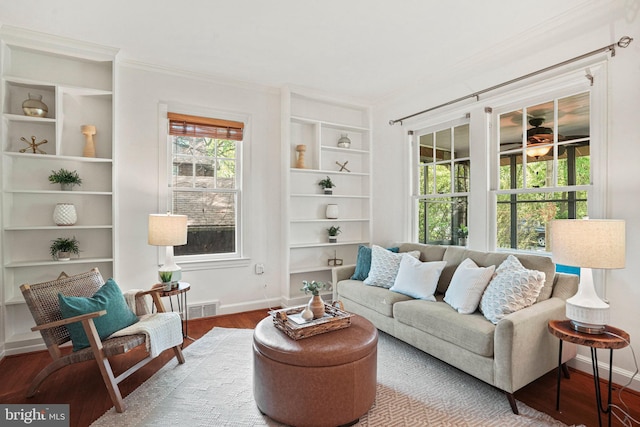 living area with visible vents, crown molding, wood finished floors, built in shelves, and baseboards