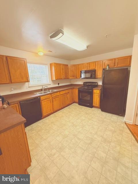 204 Carsons Ct, Pocomoke City, MD 21851 - kitchen featuring light floors, brown cabinetry, a sink, and black appliances