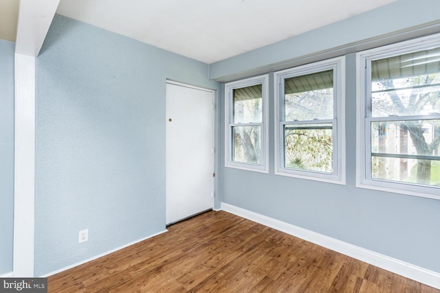 unfurnished room with baseboards, plenty of natural light, and wood finished floors