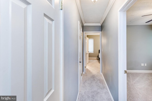 hallway featuring baseboards, ornamental molding, and carpet floors